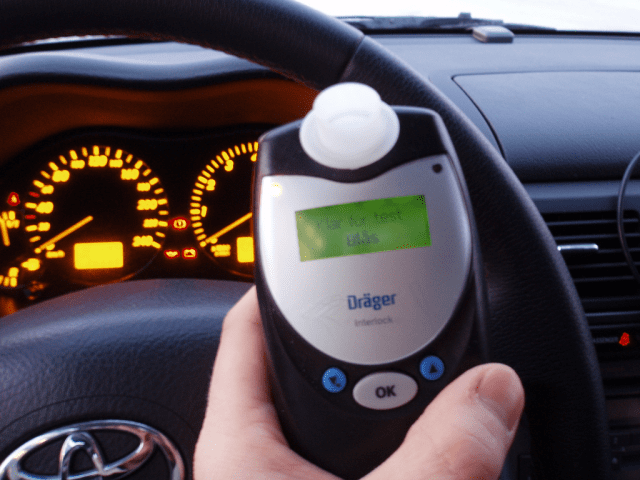 Two people examining an ignition interlock device
