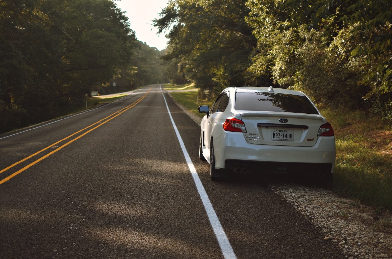 A picture of a small car parked on the side of the road waiting for roadside assistance.